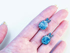 A pair of handcrafted aquamarine earrings held in hand to demonstrate scale and craftsmanship