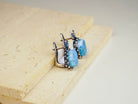 Frontal view of the bohemian style aquamarine earrings on a textured stone surface