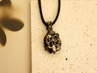 Perspective shot of the raw black crystal necklace, showing the metallic shimmer and unique silver cage design