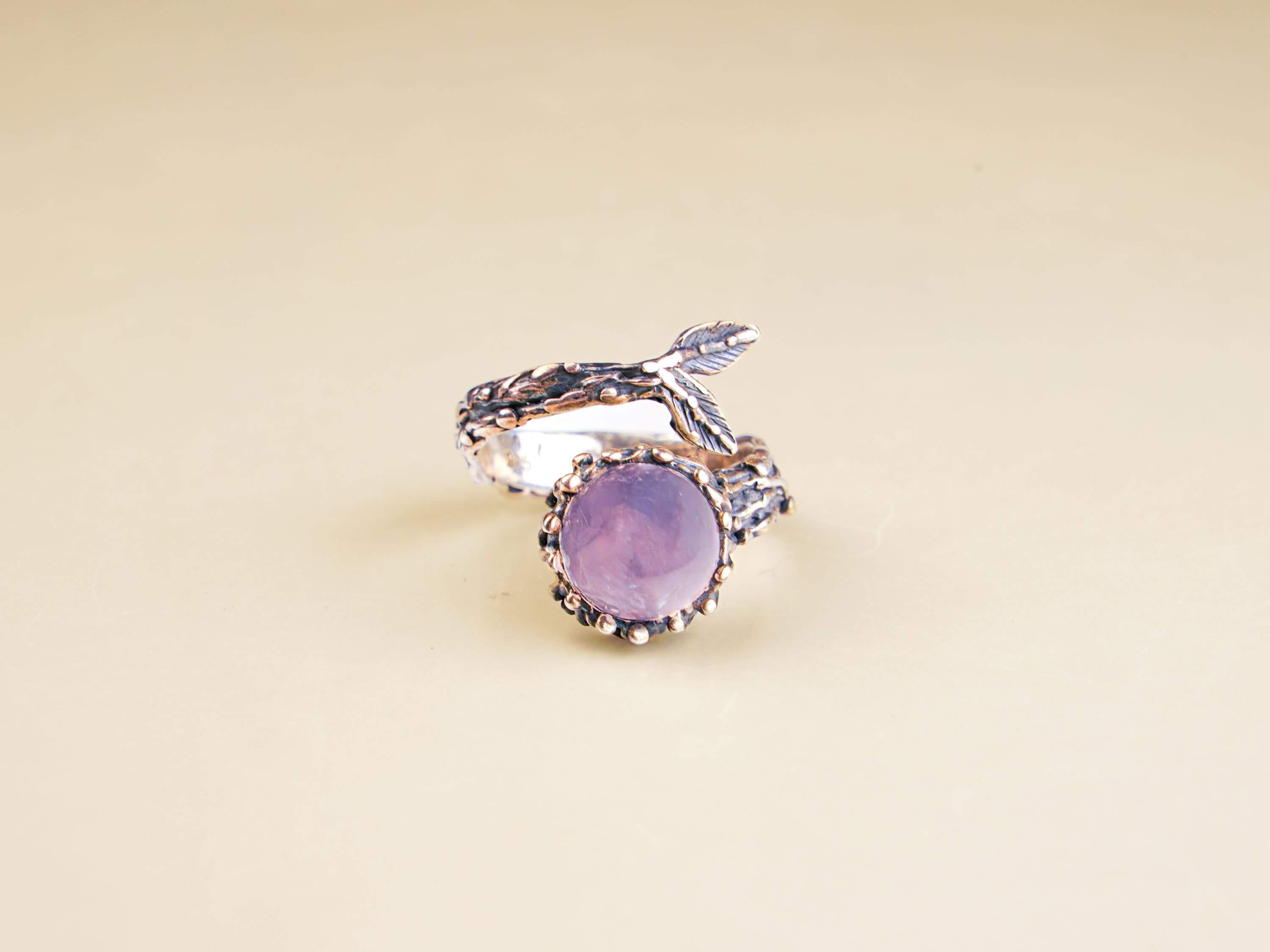 Bohemian rose quartz gemstone ring displayed on a minimalist white geometric pedestal