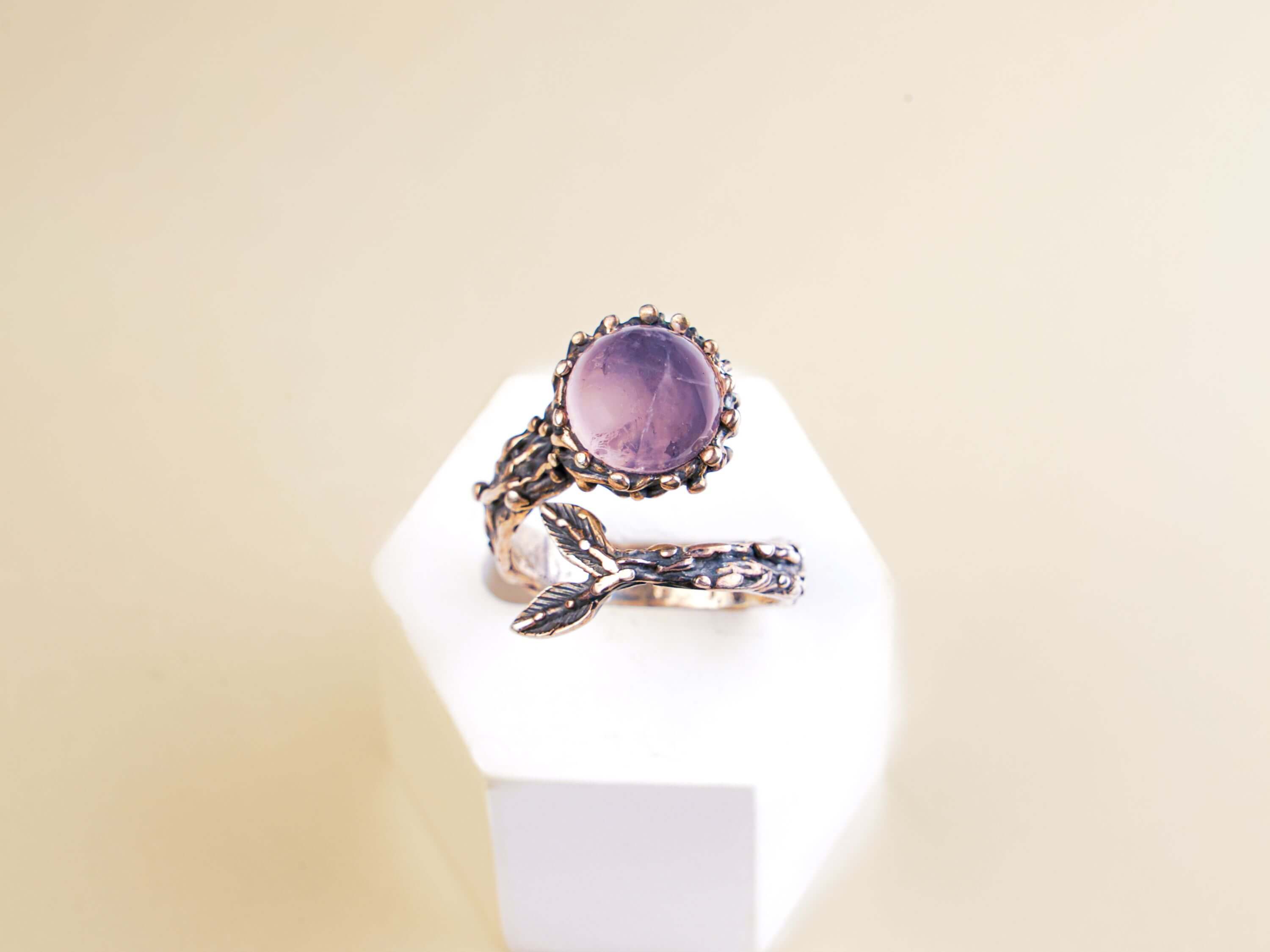 Frontal view of a light pink rose quartz ring highlighting the artistic silver leaf accents