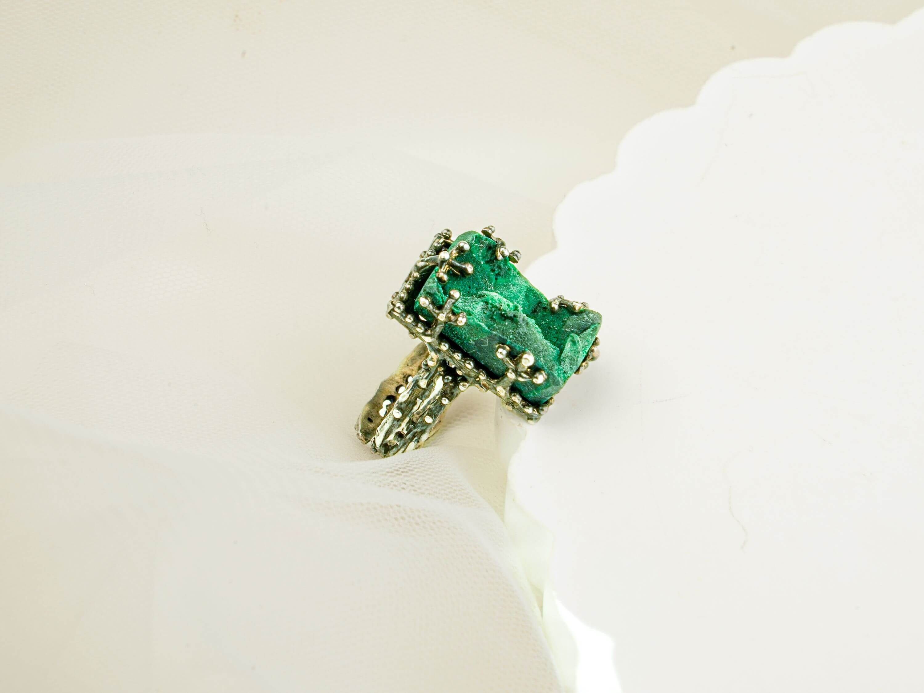 High-angle shot of a rectangular emerald green malachite ring on a white decorative platform