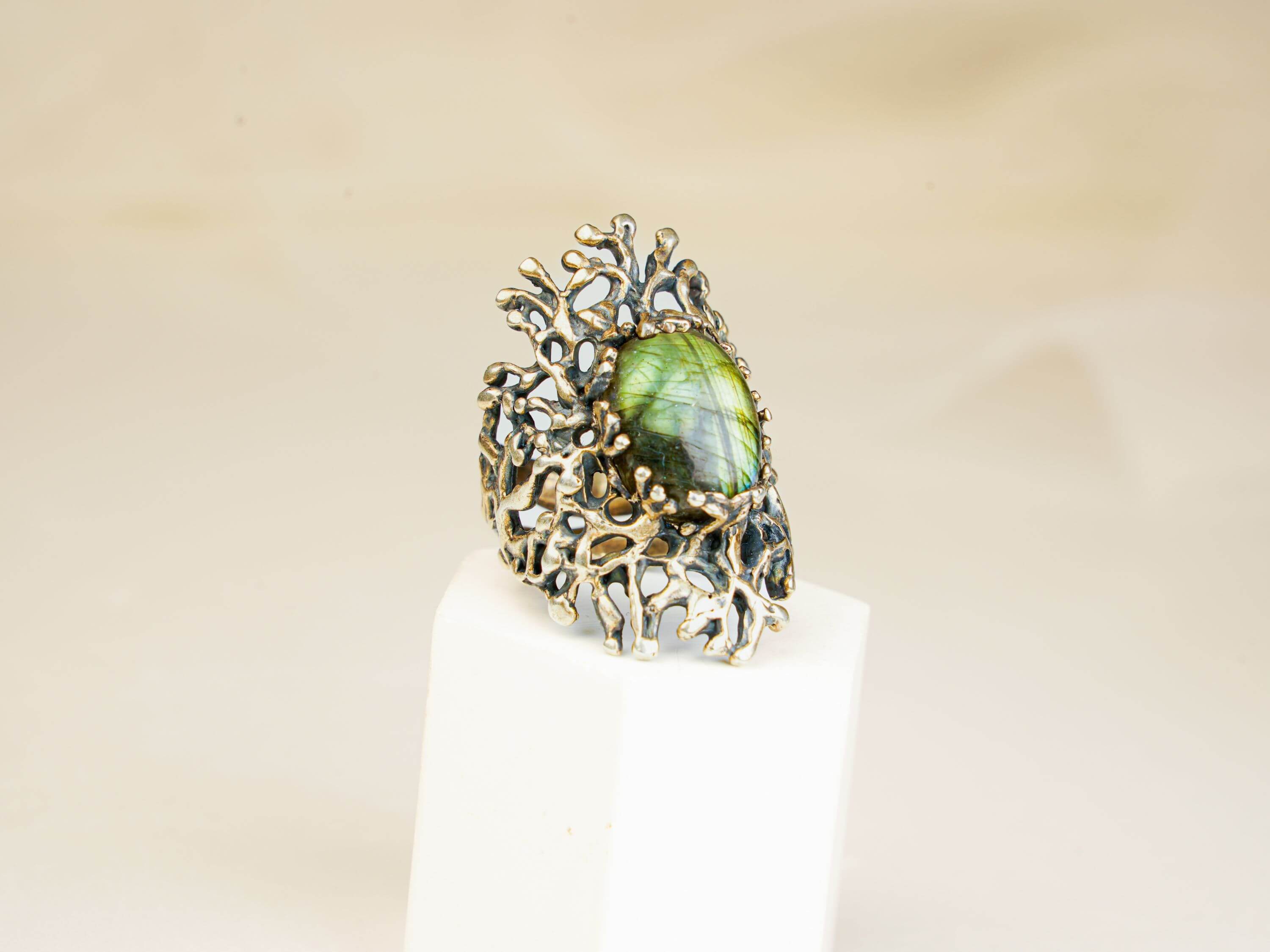 Vertical shot of a handcrafted gothic style silver ring with a glowing green labradorite