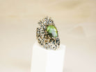 Vertical shot of a handcrafted gothic style silver ring with a glowing green labradorite