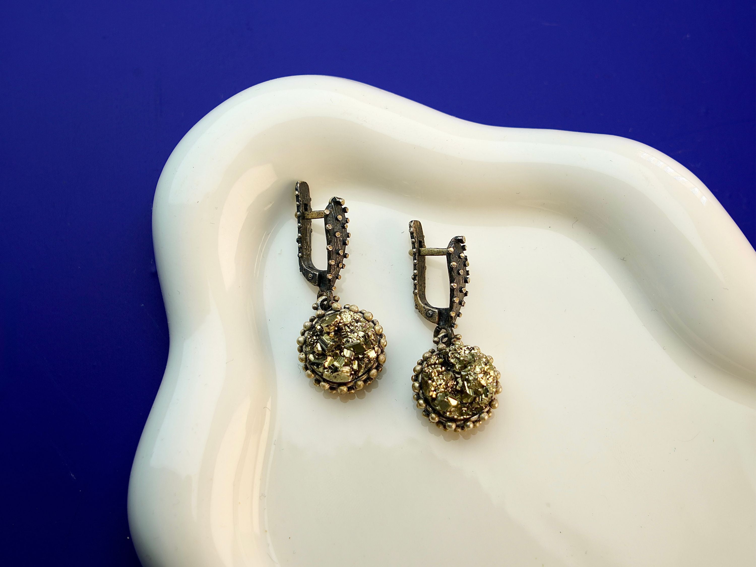 Lifestyle pyrite earrings metallic gold statement jewelry styled composition