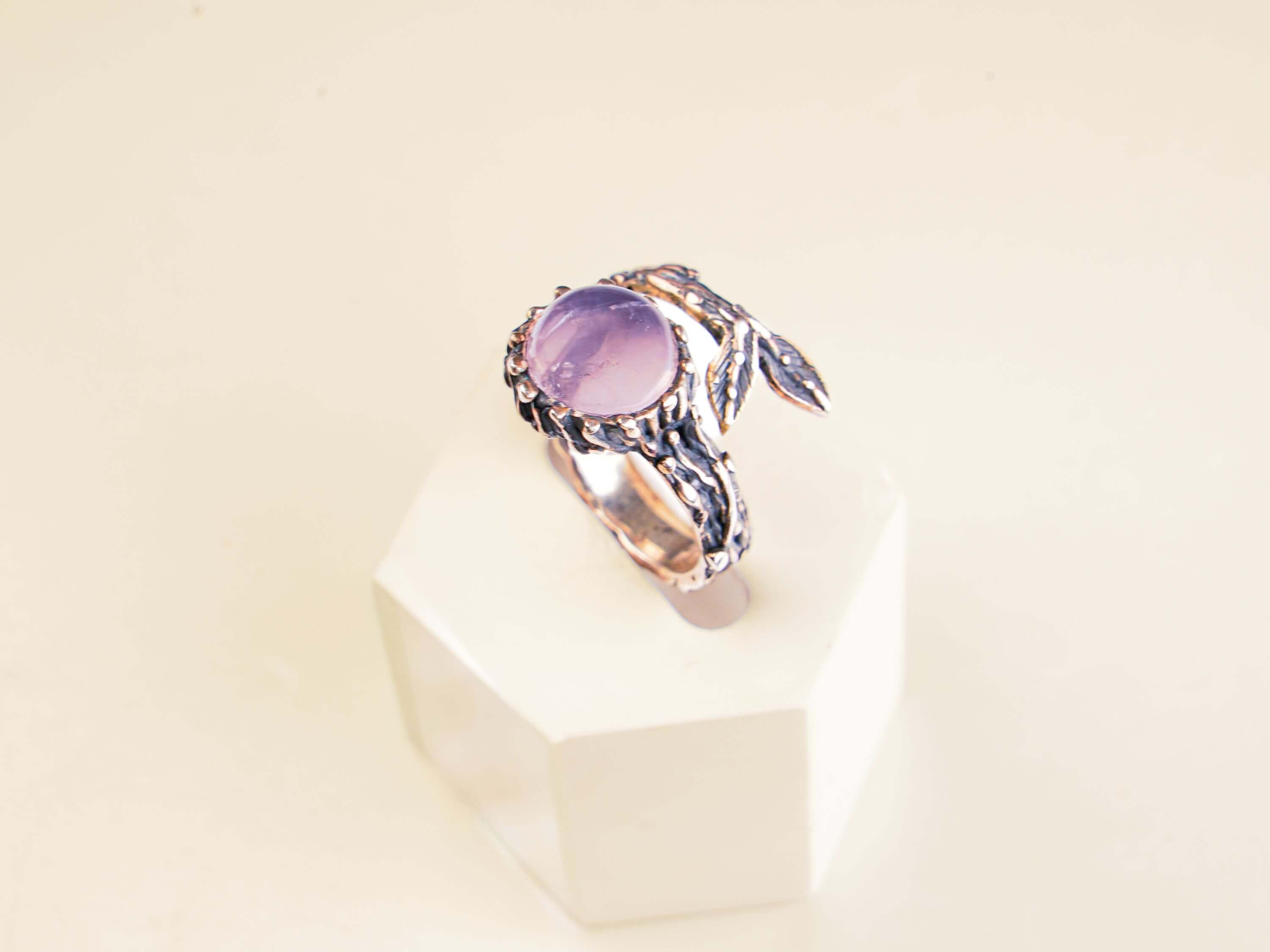 Top-down aesthetic shot of a natural rose quartz ring on a clean, modern background.