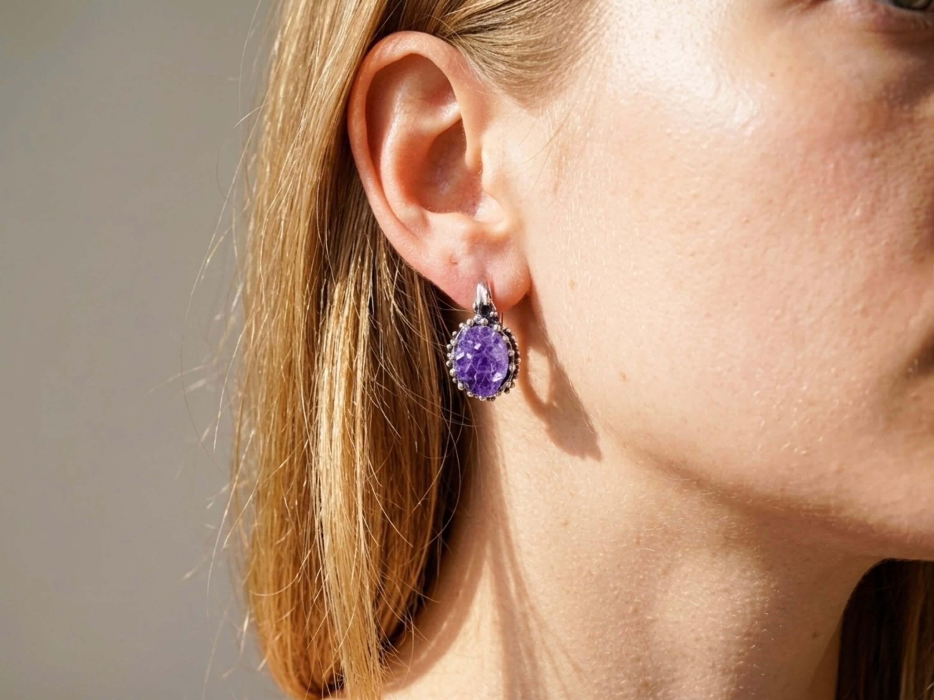 Model wearing Akra Gems raw amethyst earrings, showing the elegant oval drop and vibrant purple crystal color