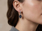 A model wearing Akra Gems raw black tourmaline earrings, showing how the bold oval shape and dark gemstone complement an elegant look