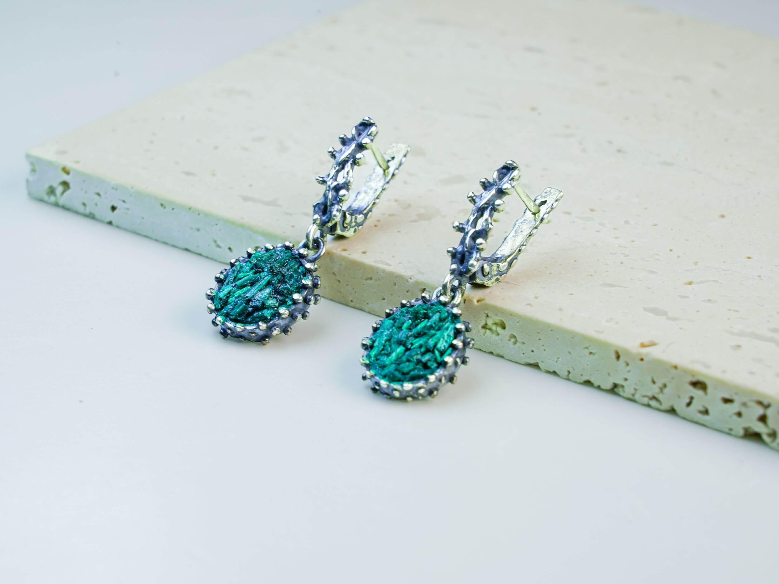 A direct front view of both Malachite drop earrings, emphasizing the symmetry, the detailed silver frames, and the bold green stone colors
