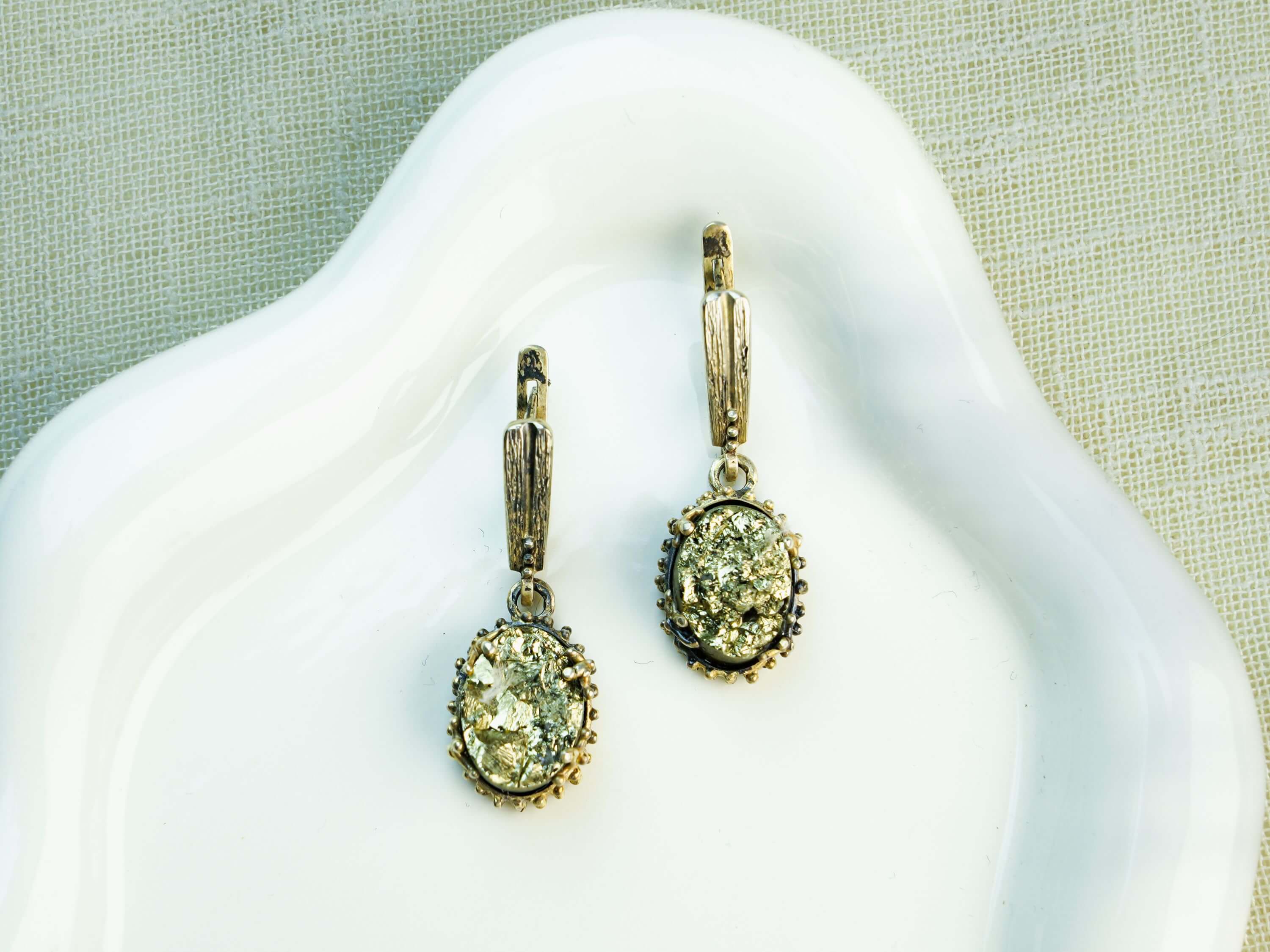 Oval Golden Pyrite earrings featuring glistening metallic gemstones in a detailed sterling silver frame, displayed on a clean background