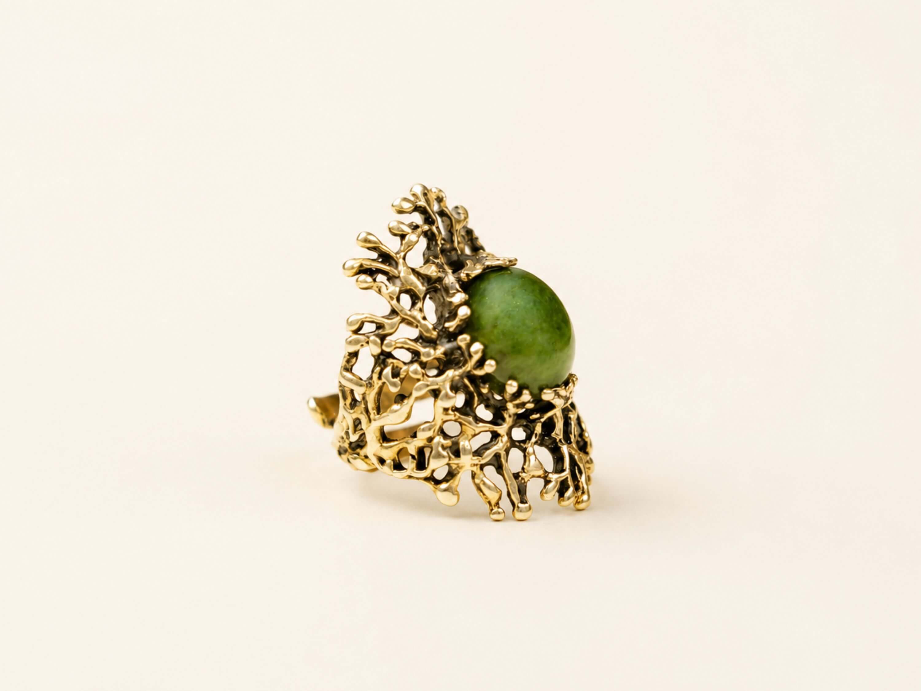 A massive green Jade statement ring featuring an intricate, organic sterling silver setting, displayed on a minimalist background.