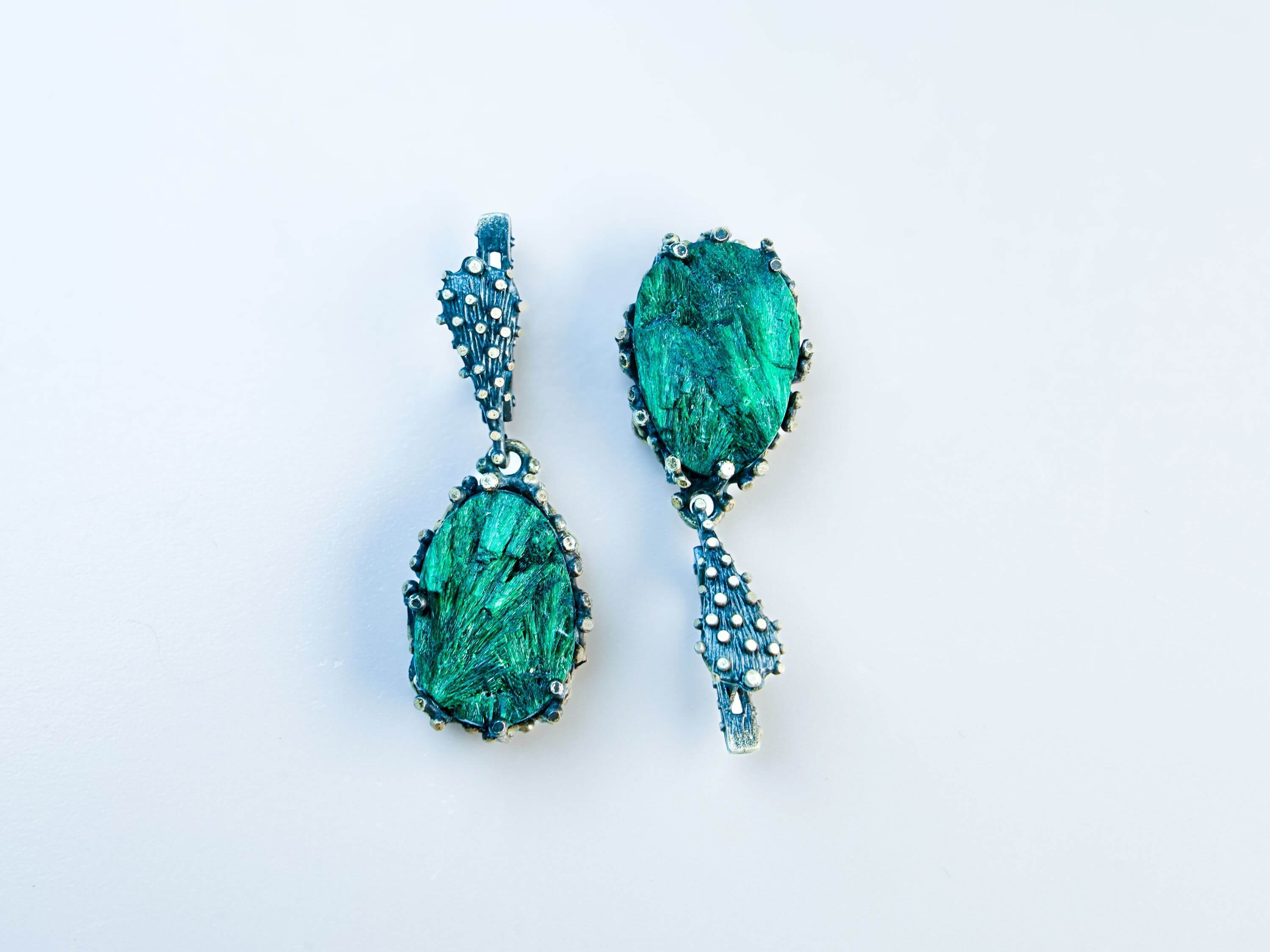 Direct front-facing view of the pear-shaped earrings, emphasizing the symmetry and the rich texture of the silver setting