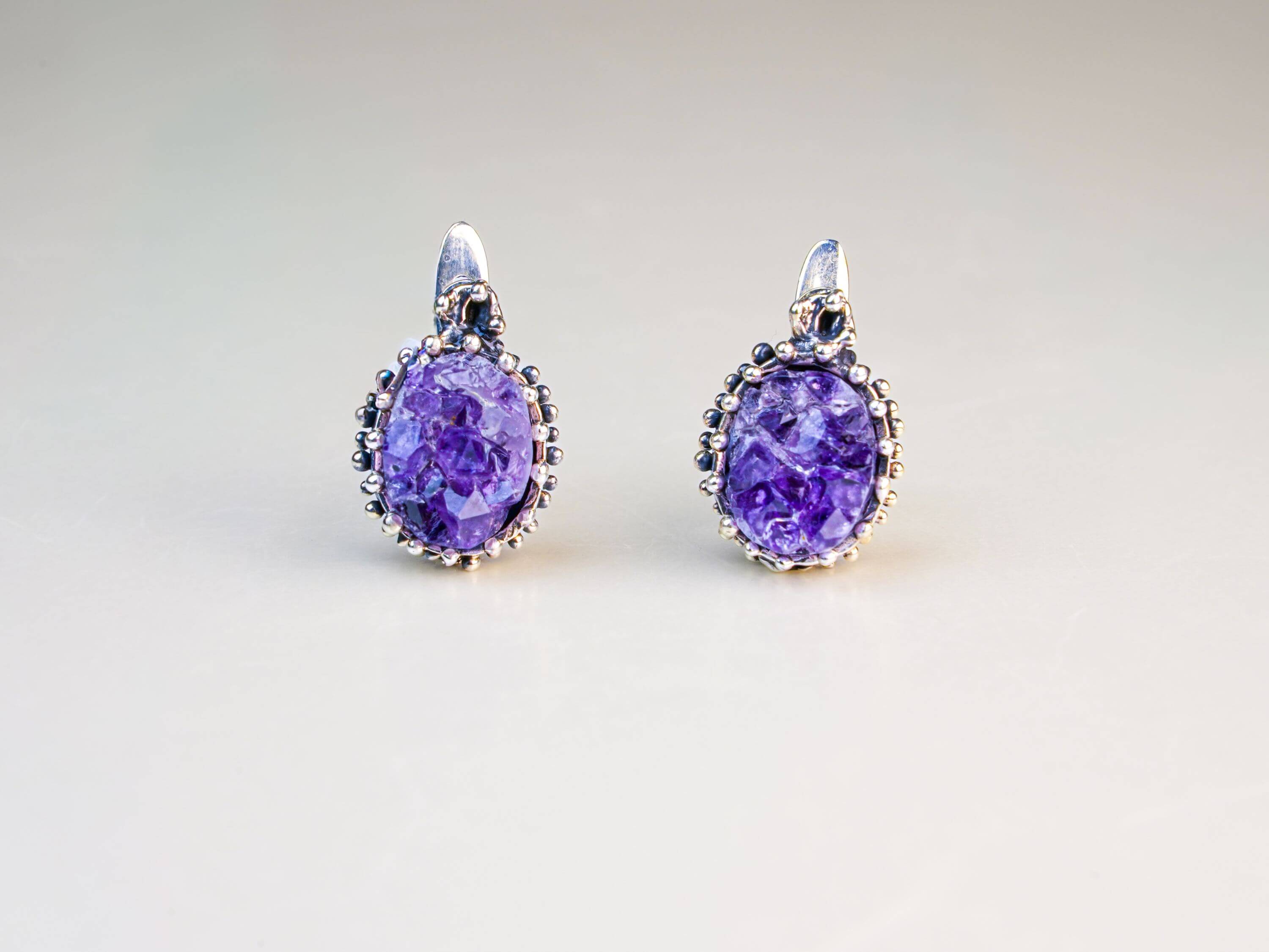 Direct front-facing view of the oval crystal earrings, emphasizing the symmetry and the intricate silver textures