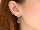 Handmade labradorite earrings worn on ear, showcasing the elegant drop style and blue gemstone flash