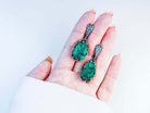 Handheld shot of both malachite dangles, demonstrating the bold statement size and handcrafted silver frame