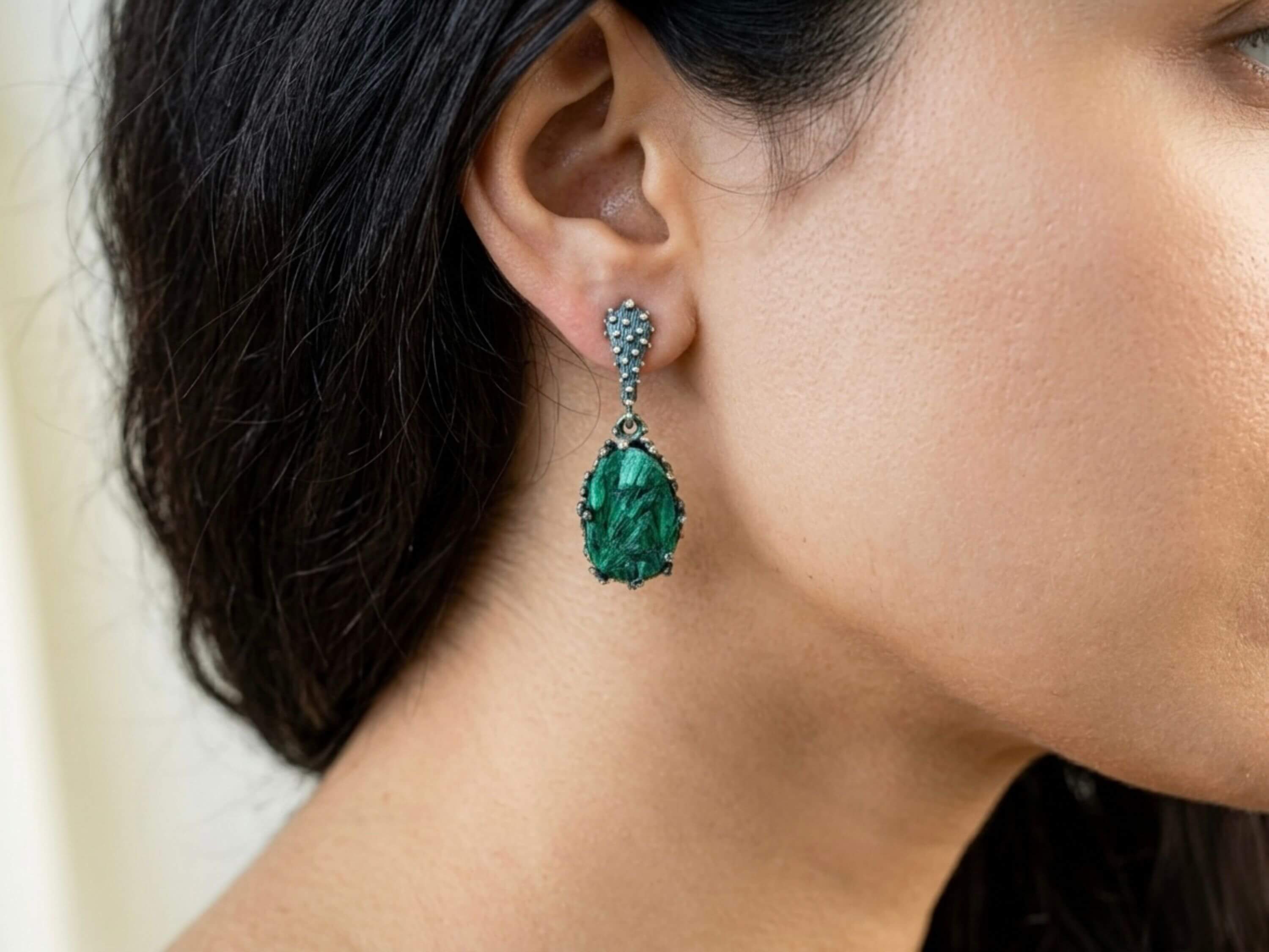 Model wearing pear-shaped Akra Gems malachite earrings, showing the elegant drop length and vibrant green color