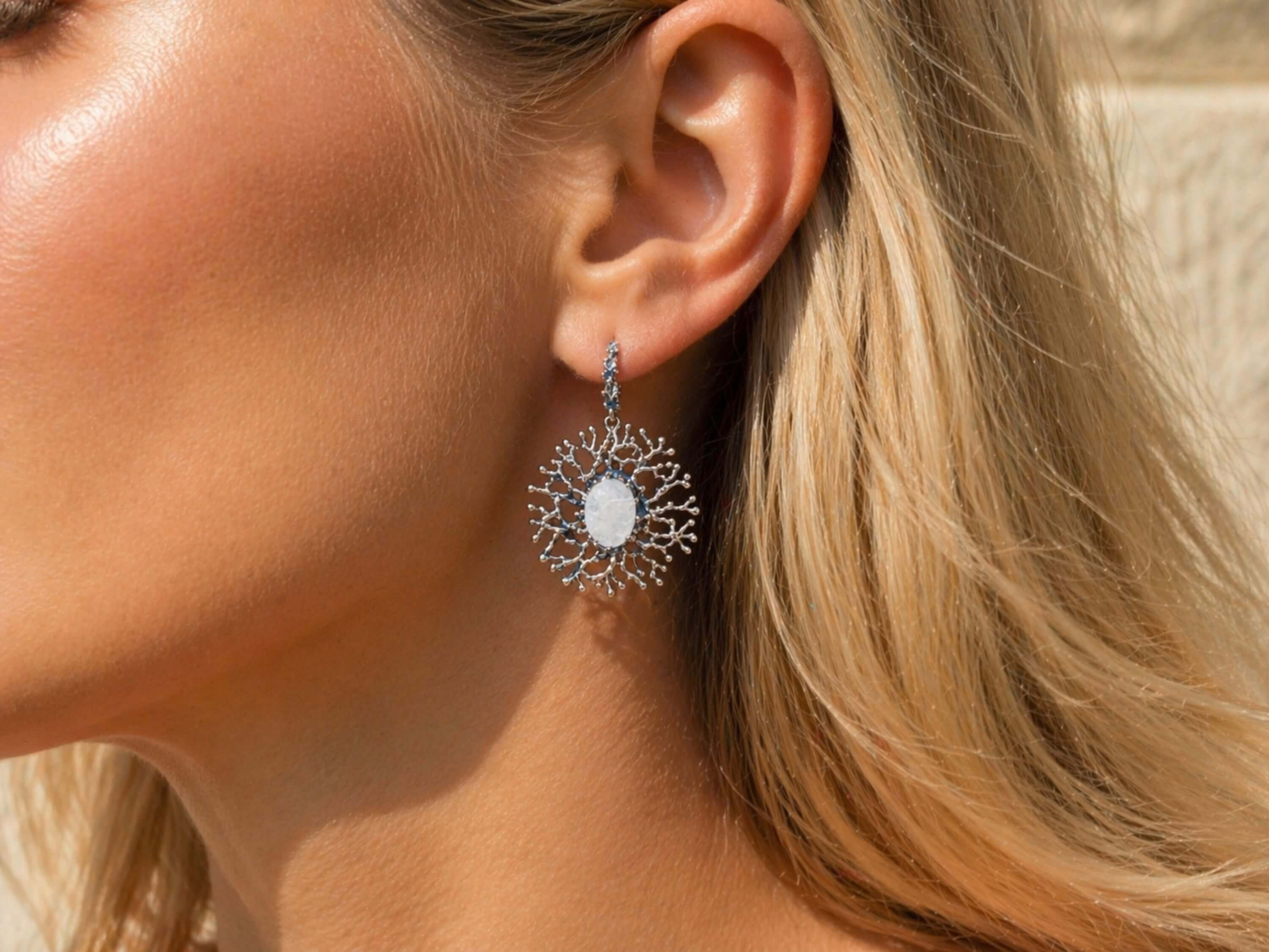 Lifestyle view of a woman wearing Akra Gems branch-style Moonstone earrings, showing the artistic scale and organic flow of the jewelry