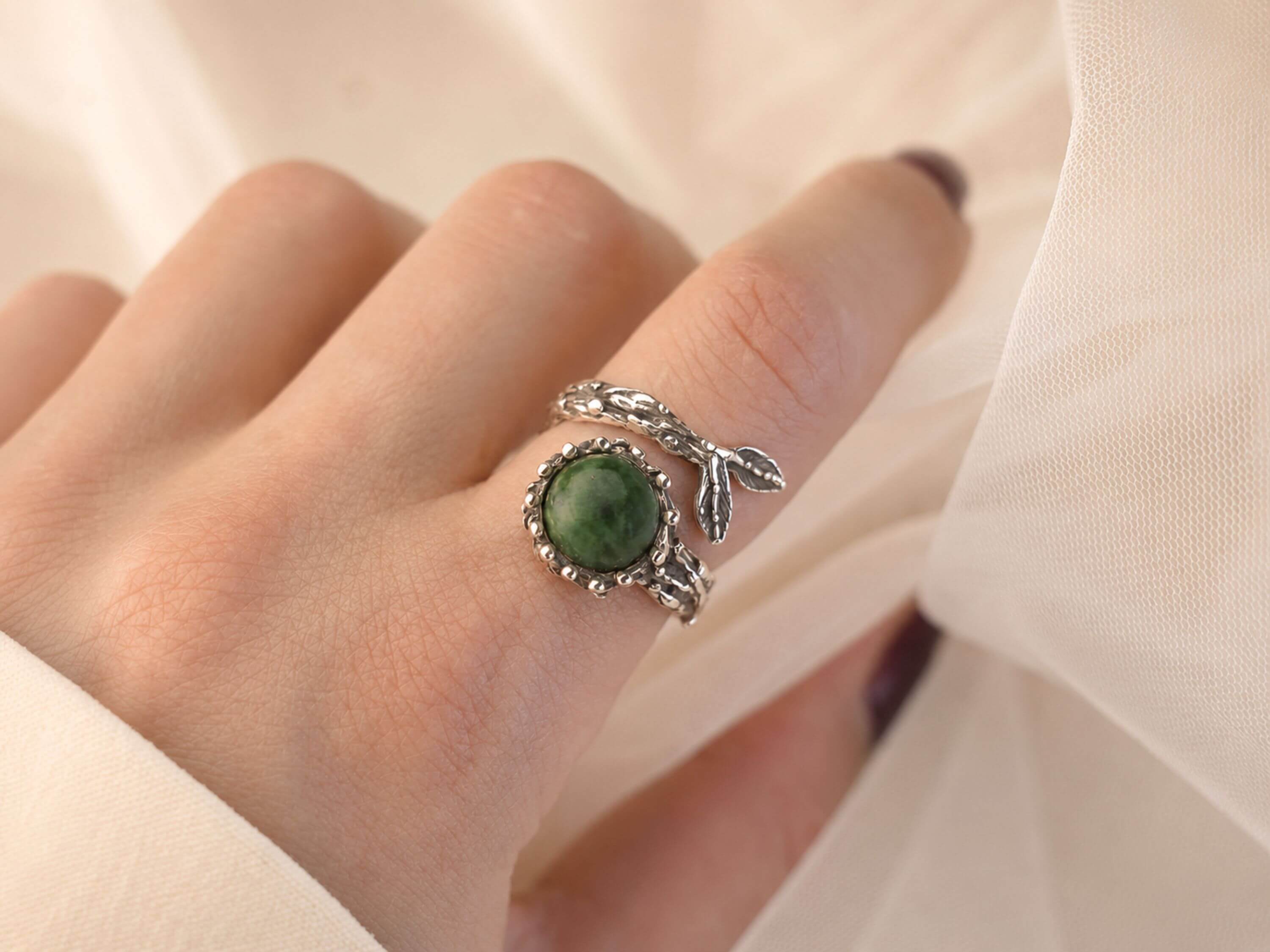 A model wearing the raw Jade ring on a finger, showing its bold scale and how the vibrant green gemstone stands out as a statement piece.