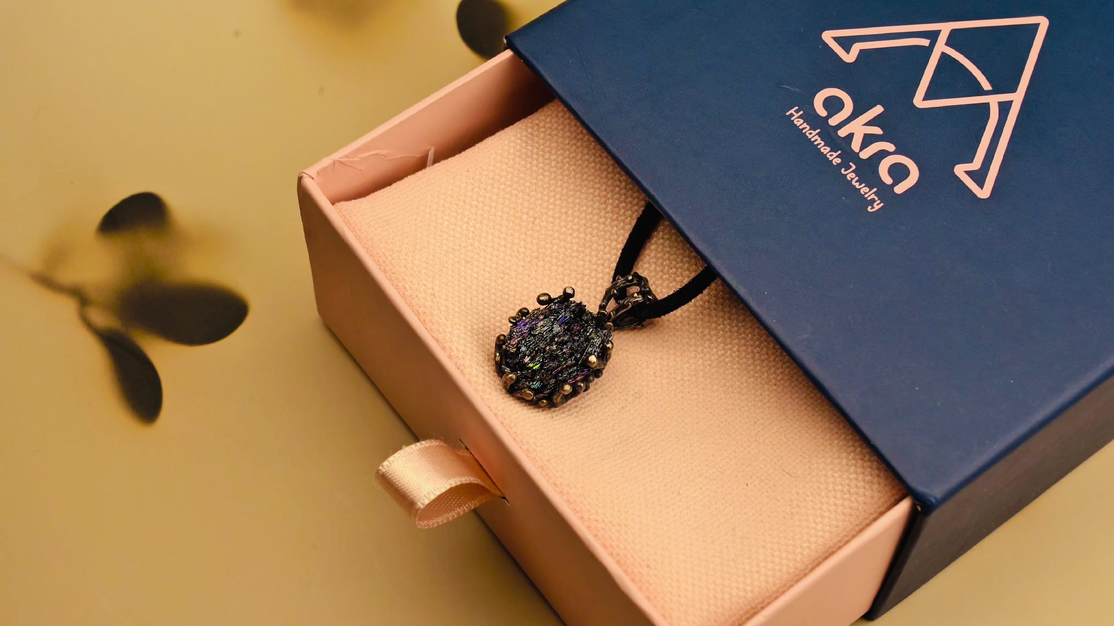 A close-up rotation of the raw black crystal pendant, displaying its natural texture, shimmering gothic silver setting, and elegant handmade gift packaging