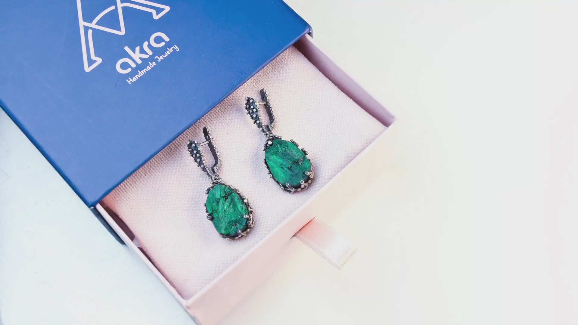 Video tour of teardrop malachite earrings, showing the 360-degree detail of the silver frame and the natural light reflecting off the green stone patterns