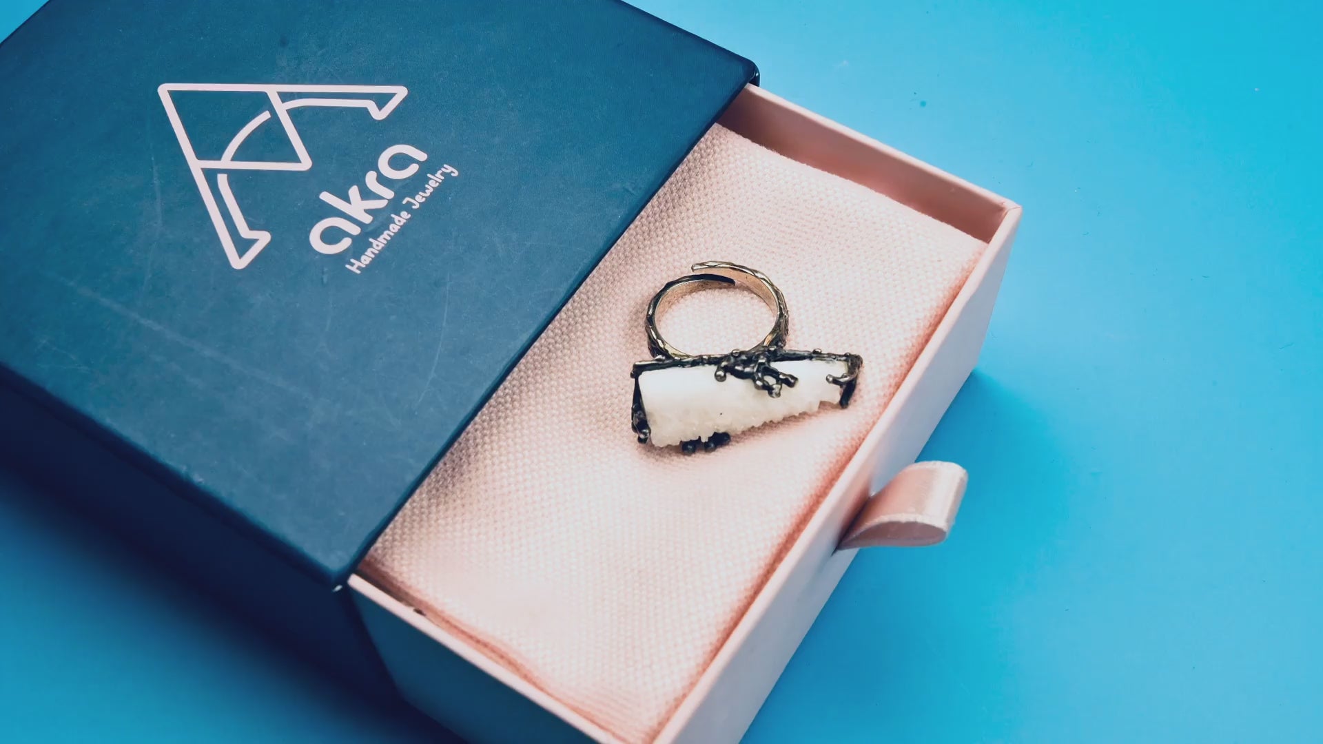 A detailed product video showcasing the raw white Moonstone ring, highlighting the unique crystalline texture of the stone and the dark, handcrafted oxidized sterling silver setting as it rotates.